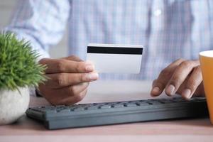 mani dell'uomo che tengono la carta di credito e utilizzano il laptop per lo shopping online