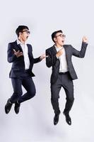 due uomini d'affari asiatici che saltano su sfondo bianco foto
