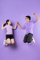 giovane coppia asiatica che salta su sfondo viola foto