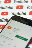 Youtube App su Samsung smartphone schermo su carta bandiera con piccolo Youtube loghi e iscrizioni. Youtube è Google filiale e americano maggior parte popolare condivisione video piattaforma foto