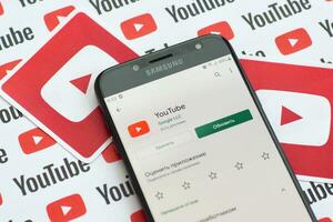 Youtube App su Samsung smartphone schermo su carta bandiera con piccolo Youtube loghi e iscrizioni. Youtube è Google filiale e americano maggior parte popolare condivisione video piattaforma foto