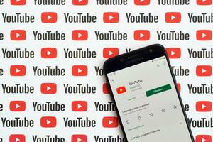 Youtube App su Samsung smartphone schermo su carta bandiera con piccolo Youtube loghi e iscrizioni. Youtube è Google filiale e americano maggior parte popolare condivisione video piattaforma foto