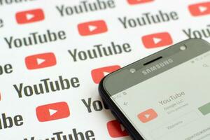 Youtube App su Samsung smartphone schermo su carta bandiera con piccolo Youtube loghi e iscrizioni. Youtube è Google filiale e americano maggior parte popolare condivisione video piattaforma foto