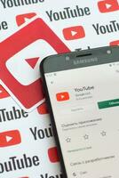 Youtube App su Samsung smartphone schermo su carta bandiera con piccolo Youtube loghi e iscrizioni. Youtube è Google filiale e americano maggior parte popolare condivisione video piattaforma foto