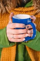 la mano di una donna che tiene una tazza di caffè caldo