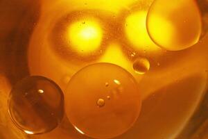 oro olio bolle vicino su. cerchi di arancia acqua macro. astratto brillante giallo sfondo foto