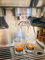 doppio colpo di caffè espresso in fase di estrazione dalla macchina foto