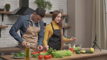 giovane coppia che cucina insieme e registra un blog di cibo video sulla fotocamera in cucina a casa