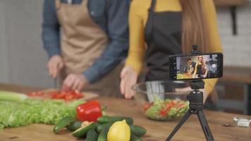 giovane coppia che cucina insieme e registra un blog di cibo video sulla fotocamera in cucina a casa. concentrati sullo schermo del telefono