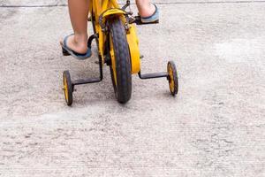 bambini con ciabatte in bicicletta con rotelle foto