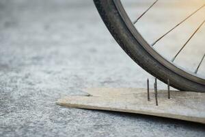 vicino su Chiodi su legna tavola e piatto bicicletta pneumatico. concetto, pericoloso , danno. essere attento e Guarda in giro durante Ciclismo su il pavimento o rischio posti. incidente può essere accaduto. foto