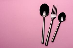 cucchiaio e forchetta di metallo isolati su sfondo rosa