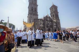 puebla, Messico 2023 - preti e membri di il cattolico Chiesa trasportare su un' processione nel davanti di il Cattedrale di puebla. culto di cattolico cristiano simboli foto
