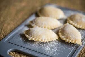 crudo Ravioli . Ravioli cucinando su un' cucina taglio tavola. foto