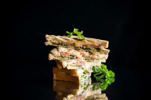 fritte toast ripieno con salsiccia, formaggio e verdura dentro, su nero sfondo. foto