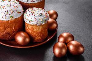 uova di pasqua oro e bronzo e torta di pasqua su sfondo scuro foto
