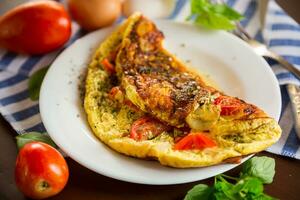 ripieno frittata con pomodori su un' leggero di legno sfondo. foto