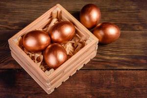 uova di pasqua in scatola regalo di legno su fondo di legno scuro foto