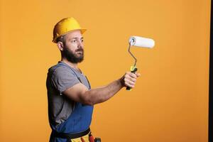 professionale tuttofare utilizzando rotolamento spazzola per fare pittura lavoro, Lavorando su Restaurare progetto per colore muri. riparatore contraente Tenere rullo pennello per ristrutturazione e ristrutturazione. foto