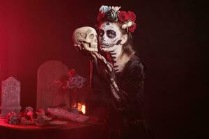 Santa muerte modello Tenere cranio nel studio, recitazione pauroso e orrore per celebrare messicano Halloween. bellissimo donna nel Festival costume con corpo arte, guardare piace dea di Morte. foto