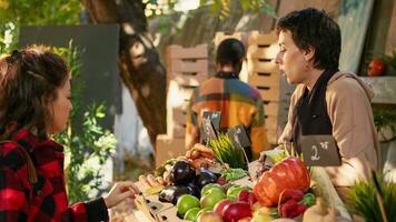 amichevole femmina venditore vendita fresco naturale mele per consumatore, in piedi dietro a agricoltura produrre contatore. Locale contadino mostrando frutta e verdure per cliente, salutare nutrizione. foto