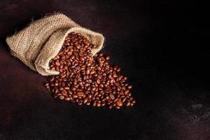 chicchi di caffè tostato fresco primo piano su uno sfondo scuro foto