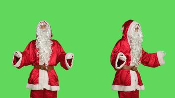 Santa Claus festivo incarnazione su dicembre celebrazione in posa al di sopra di schermo verde sfondo. fiducioso giovane uomo nel di stagione inverno costume con bicchieri e barba, diffusione felicità. foto