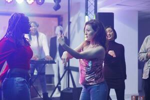 energico donne ballerini improvvisando si sposta mentre discoteca e godendo vita notturna tempo libero attività. amiche fare danza battaglia su pista da ballo a discoteca festa nel discoteca foto