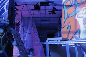 demolito struttura con neon luci trasformato in caos, abbandonato urbano edificio raggiante nel il buio di abbandonato magazzino. trascurato spazio con fluorescente viola splendente luce. foto