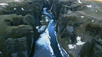 spettacolare fjadrargljufur canyon aereo Visualizza con acqua ruscello e islandese scenario, nevoso montagne e massiccio rocce. maestoso nordico paesaggio con fiume fluente fra colline. lento movimento. foto