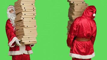 natale personaggio con pila di Pizza scatole, trasporto grande mucchio di consegna cibo, persona indossare festivo personaggio Santa Claus costume con bianca barba. uomo in piedi al di sopra di schermo verde. foto