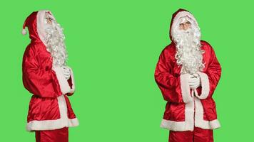 gioioso persona nel festivo rosso completo da uomo recitazione piace Santa claus, diffusione Natale spirito su schermo verde. contento uomo raffigurante festivo di stagione personaggio con tradizionale costume, cappello e barba. foto