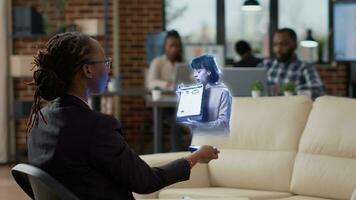 bipoc dipendente nel Augmented la realtà Teleconferenza incontro nel alto Tech ufficio parlando con collaboratore. contabile a posto di lavoro scrivania nel in linea video chiamata con manager utilizzando ologramma tecnologia foto