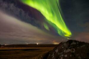 a tramonto nel Islanda, aurora Borealis illumina su notte cielo nel eccezionale tonalità di verde e Viola, formatura magico islandese paesaggio. stelle scintillare in giro settentrionale luci. foto