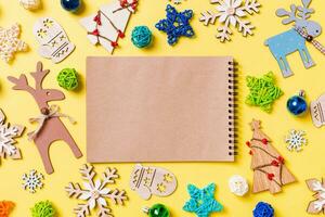 superiore Visualizza di taccuino su giallo sfondo con nuovo anno giocattoli e decorazioni. Natale tempo concetto foto