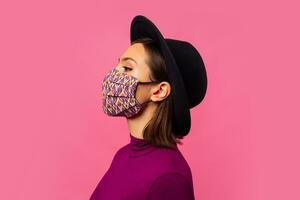 studio foto di giovane brunetta ragazza indossare respiratorio viso maschera contro coronavirus. sfondo di rosa colore con copia spazio.