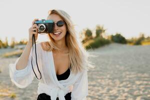 elegante ragazza con retrò telecamera su soleggiato spiaggia. estate vacanza. la libertà e viaggio concetto. foto