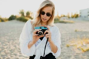 elegante ragazza con retrò telecamera su soleggiato spiaggia. estate vacanza. la libertà e viaggio concetto. foto