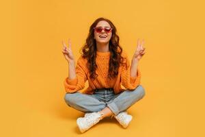 bella fricchettone rosso testa ragazza nel elegante autunno equipaggiamento in posa al di sopra di giallo sfondo. foto