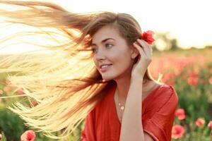 grazioso bionda donna in posa all'aperto. ventoso capelli. pittoresco papavero campo nel caldo tramonto colori. foto