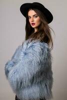 studio moda ritratto di bellissima donna nel elegante inverno soffice blu cappotto e nero cappello. foto