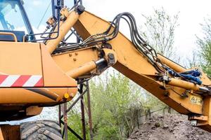 il moderno escavatore esegue lavori di scavo in cantiere foto