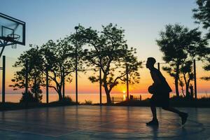 nero uomo fare gli sport, giocando pallacanestro su Alba, silhouette foto
