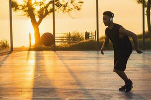 nero uomo fare gli sport, giocando pallacanestro su Alba, attivo stile di vita, soleggiato estate mattina foto