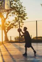 nero uomo fare gli sport, giocando pallacanestro su Alba, attivo stile di vita, soleggiato estate mattina foto