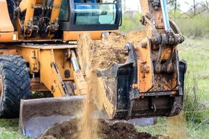 il moderno escavatore esegue lavori di scavo in cantiere foto