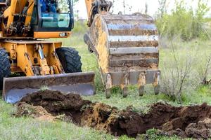 il moderno escavatore esegue lavori di scavo in cantiere foto