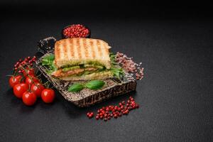 delizioso croccante Sandwich con pane abbrustolito, salmone, avocado, pomodori, sale, spezie e erbe aromatiche foto