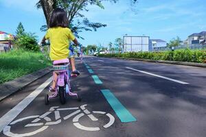 poco ragazza è equitazione sua bicicletta foto