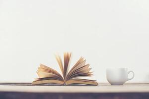 vecchio libro d'annata con la tazza di caffè sul fondo di legno della tavola della piattaforma. foto